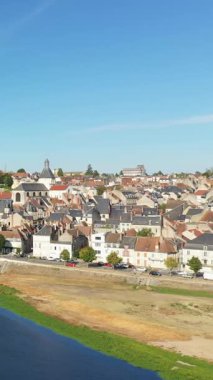 Fransa 'nın La Charite-sur-Loire şehrinin tarihi çatılarının ve nehir kıyısının açık mavi gökyüzünün altında manzaralı manzarası. Resimli eski kasaba mimarisi ve sakin atmosferi.
