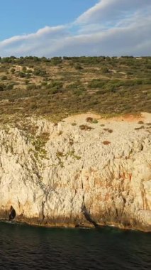 Yunanistan 'ın Mani bölgesindeki Diros Sahili' nin kıyısındaki engebeli uçurumların ve berrak mavi denizin manzarası, parçalı bulutlu bir gökyüzünün altında..
