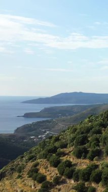 Yunanistan 'ın Vathia kentindeki berrak mavi gökyüzünün altında sakin bir kıyı şeridine bakan yemyeşil tepeler. Huzurlu Akdeniz manzarası seyahat ve doğa kavramları için ideal.