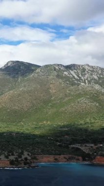 Yunanistan 'ın Monemvasia kenti yakınlarındaki kıyı şeridi boyunca parçalı bulutlu bir gökyüzünün altında engebeli dağların ve berrak mavi denizin manzarası..