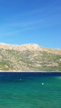 Porto Kagio, Yunanistan 'da berrak bir gökyüzü altında berrak mavi deniz ve engebeli tepeler. Sakin doğal manzara seyahat ve doğa kavramları için idealdir..