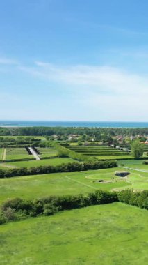 Fransa 'nın Normandiya kentindeki Battery de Merville' deki yeşil alanlar, çalılar ve tarihi sığınakların manzaralı manzarası, açık mavi gökyüzünün altında kıyı şeridi görülebiliyor..