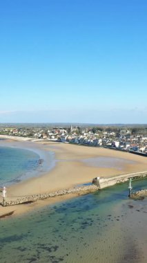 Fransa 'nın Normandiya kentinde kumlu sahil ve sahil kenti Grandcamp-Maisy' nin açık mavi gökyüzünün altında manzarası..