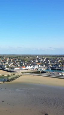 Açık bir günde kumlu sahil manzarası, liman ve geleneksel evler Grandcamp-Maisy, Normandiya, Fransa.