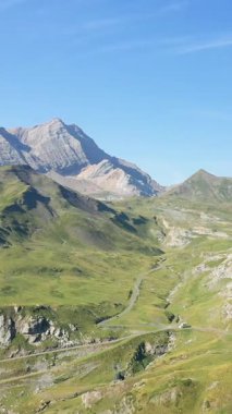 Yeşil tepelerin yuvarlanan manzarası ve Pireneler 'deki engebeli tepeler berrak mavi bir gökyüzünün altında. Dönen yolları ve kayalık arazisi olan doğal yaz manzarası.