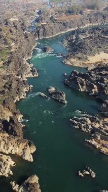 Laos 'ta Tat Somphamit Li Phi şelalesinin engebeli kayalarla dolu nehir kanyonunun ve akan suyun hava manzarası. Doğal dokuları ve canlı renkleriyle dramatik bir manzara..