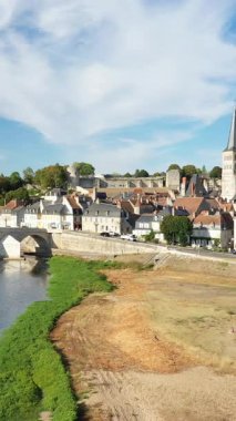 La Charite sur Loire manzarası. Geleneksel evler, taş bir köprü ve parlak bir gökyüzünün altındaki Loire nehri. Resimli Fransız köyü atmosferi.