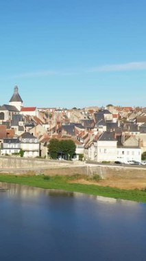 Fransa 'nın La Charite-sur-Loire kentindeki geleneksel çatı ve kilise kulesinin büyüleyici manzarası. Açık mavi gökyüzünün altında Loire Nehri var..