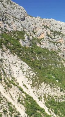 Fransa 'nın Verdon Vadisi' ndeki açık mavi gökyüzünün altında dağınık yeşil bitki örtüsü olan dik kireçtaşı kayalıkları. Engebeli doğal manzara açık hava ve macera temaları için ideal..