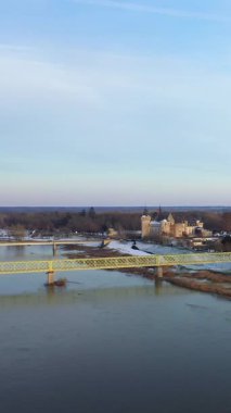 Sully-sur-Loire kalesinin hava manzarası ve Fransa 'da karlı bir kış manzarasıyla çevrili Loire Nehri üzerindeki bir köprü..