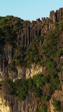 Vietnam, Ha Long Körfezi 'nde yemyeşil bitki örtüsü olan dramatik kireçtaşı kayalıkların yakın görüntüsü, sıcak günbatımı ışığı ile aydınlatılıyor..