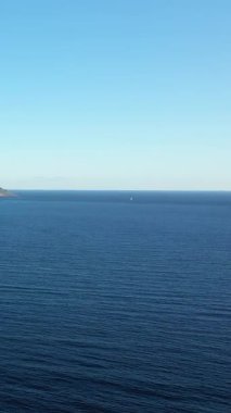 Uzak bir yelkenli ile berrak bir gökyüzünün altındaki sakin mavi deniz manzarası Porto Badisco, İtalya. Huzurlu deniz manzarası seyahat ve doğa kavramları için idealdir.