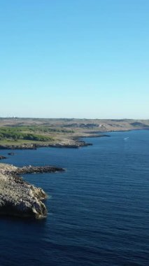 İtalya 'nın Porto Badisco şehrinde kayalık kıyı şeridi ve açık bir gökyüzünün altında derin mavi deniz manzarası. Engebeli kıyı şeridi ve sakin sular sakin bir doğal manzara yaratır..