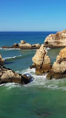 Dalgalar, Portekiz 'in Albufeira yakınlarındaki Algarve kıyı şeridi boyunca uzanan engebeli kireçtaşı kayalıklarına ve kaya oluşumlarına çarpar..