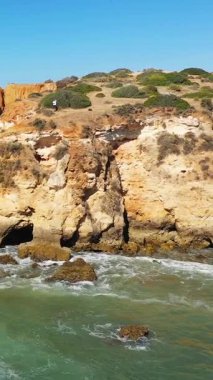 Portekiz 'in Albufeira kenti yakınlarındaki Algarve kıyısındaki dramatik kayalık ve deniz mağaraları, güneşli bir günde aşağıdan gelen turkuaz dalgalar..