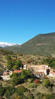 Yunanistan 'da açık mavi bir gökyüzü altında yemyeşil ve dağlarla çevrili tarihi Osios Loukas Manastırı' nın havadan görünüşü.