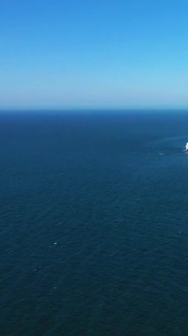 Açık bir gökyüzünün altındaki derin mavi denizin geniş bir görüntüsü, uzak beyaz bir uçurum kenarı görünür, Etretat, Fransa yakınlarında çekildi..