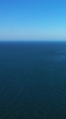 Derin mavi okyanusun açık mavi gökyüzü ile buluşmasının geniş bir görüntüsü, Fransa 'nın Etretat sahilinde çekildi. Görünürde kara veya nesne olmayan sakin deniz manzarası.