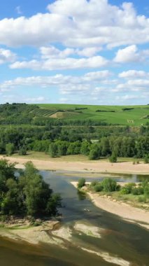 Fransa, Pouilly 'de bulutlu mavi gökyüzü altında yemyeşil üzüm bağları ve yuvarlanan tepeleriyle Loire nehrinin manzarası..