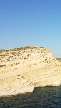 Yunanistan 'ın Girit kentindeki mavi Akdeniz' in üzerinde yükselen Matala 'nın ikonik kireçtaşı kayalıklarının manzarası, berrak bir gökyüzü altında.