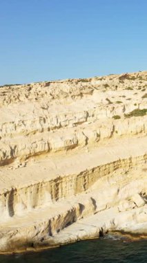 Girit Matala 'da denize bakan kireçtaşı kayalıkları ve mağaralar, üzerinde açık mavi gökyüzü var. Engebeli kaya oluşumları dramatik bir kıyı manzarası yaratır..