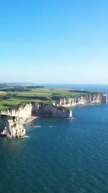 Etretat, Normandiya, Fransa kıyıları boyunca açık mavi gökyüzünün altında ikonik beyaz tebeşir ve turkuaz deniz manzarası.