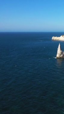 Etretat, Normandiya, Fransa kıyıları boyunca açık mavi gökyüzü altında dramatik beyaz tebeşir kayalıkları ve doğal deniz kemerinin manzarası.