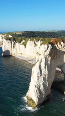 Güneşli bir günde, Etretat, Normandiya, Fransa kıyıları boyunca mavi suların üzerinde dramatik beyaz tebeşir kayalıkları ve doğal bir deniz kemeri yükselir..