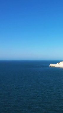 Etretat, Fransa 'da açık bir gökyüzünün altında dramatik beyaz uçurumlar bulunan derin mavi okyanus manzarası. Sakin deniz manzarası doğa, seyahat ve kıyı kavramları için idealdir..