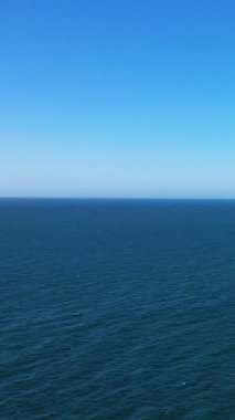 Açık bir gökyüzünün altında, Fransa 'nın Etretat sahillerinde yakalanan engin mavi okyanus. Minimalist deniz manzarası arka plan ve yaratıcı projeler için idealdir.