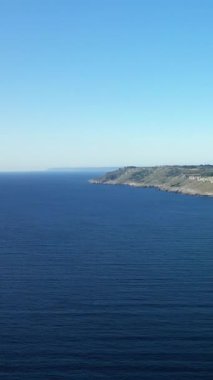 İtalya 'nın Porto Badisko kenti yakınlarında açık bir gökyüzünün altında kayalık kıyı şeridi ve derin mavi deniz manzarası. Engebeli kayalıkları ve geniş suları olan sakin deniz manzarası..