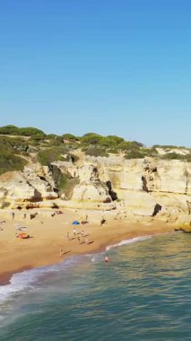 Albufeira, Portekiz yakınlarındaki Algarve kıyısında, parlak bir gökyüzünün altında, altın kayalıkların, kumlu sahillerin ve berrak mavi suların manzarası..