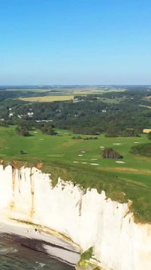 Etretat, Normandiya, Fransa 'da güneşli bir günde yemyeşil golf sahasına bakan dramatik beyaz tebeşir uçurumlarının havadan görünüşü.