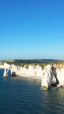 Etretat, Normandiya, Fransa 'da açık bir gökyüzü altında dramatik beyaz tebeşir kayalıkları ve doğal kemer oluşumları mavi denizin üzerinde yükselir..