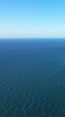 Fransa 'nın Etretat sahili açıklarında berrak bir gökyüzü ile buluşan sakin mavi denizin geniş bir görüntüsü. Huzurlu okyanus ufkuyla minimalist deniz manzarası.