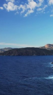 Korsika, Cargese yakınlarındaki engebeli kıyı şeridi ve açık gökyüzünün altında dağınık bulutlarla birlikte derin mavi deniz manzarası..