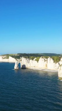 Etretat, Normandiya, Fransa 'da açık bir yaz gökyüzü altında İngiliz Kanalı' nın mavi sularının üzerinde dramatik beyaz tebeşir uçurumları yükseliyor..