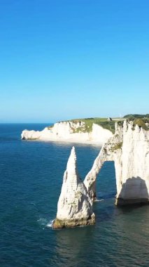 Etretat, Normandiya 'da açık bir gökyüzünün altında dramatik beyaz tebeşir kayalıkları ve mavi suların üzerinde yükselen doğal deniz kemeri..