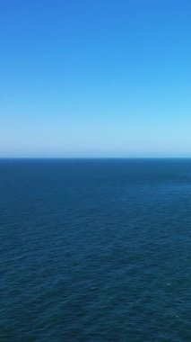 Açık denizin bulutsuz mavi gökyüzü ile buluşmasının sakin görüntüsü, Fransa 'nın Etretat sahilinde çekildi. Huzur, doğa ve seyahat kavramları için mükemmel..