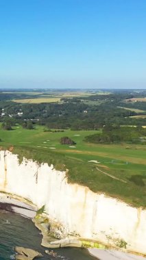 Açık bir yaz gününde Etretat, Normandiya, Fransa 'da denize bakan dramatik beyaz tebeşir kayalıklarının üzerinde bir golf sahasının havadan görünüşü.