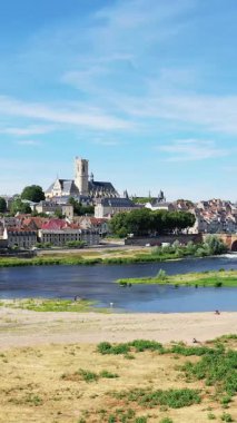 Nevers 'in tarihi mimarisi, önemli bir kilisesi ve açık mavi gökyüzünün altındaki nehir manzarası..