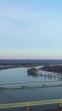 Sully-sur-Loire yakınlarındaki Loire Nehri 'nin sakin kış manzarası, karla kaplı kıyılar, yapraksız ağaçlar ve berrak bir gökyüzünün altındaki sakin suyu geçen bir köprü..
