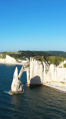 Etretat, Normandiya, Fransa 'da açık bir gökyüzünün altında İngiliz Kanalı' nın mavi sularının üzerinde dramatik beyaz tebeşir kayalıkları ve doğal deniz kemeri yükseliyor..