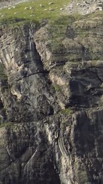 İnce bir şelale ve Fransız Pireneleri Sirki 'ndeki yeşillik parçalarıyla engebeli kayalık uçurumların yakın görüntüsü..