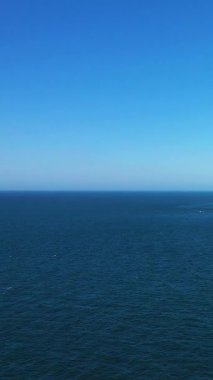 Fransa 'nın Etretat sahili açıklarında berrak bir gökyüzü ile buluşan sakin mavi denizin geniş bir görüntüsü. Minimalist deniz manzarası arka plan veya doğa kavramları için idealdir.