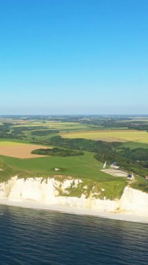 Fransa 'nın Etretat, Normandiya kıyı şeridi boyunca uzanan ikonik beyaz tebeşir kayalıkları ve yeşil alanlar açık mavi gökyüzünün altında..