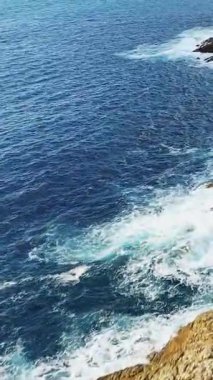 Korsika 'da Delta du Fango kıyısı boyunca engebeli kayalara çarpan derin mavi okyanus dalgalarının havadan görüntüsü. Dinamik doğal deniz manzarası köpüklü beyaz sörf ve berrak su.