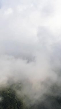 Thick clouds float over lush green mountains in Banaue, Philippines, creating a serene and atmospheric landscape.