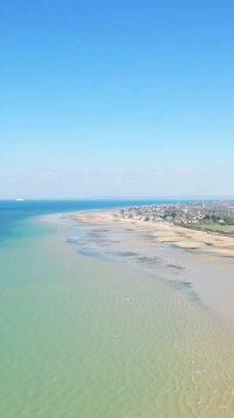 Bernieres-sur-Mer, Normandiya 'daki Juno Sahili' nin geniş kumlu kıyı şeridini ve açık mavi gökyüzünü gösteriyor..