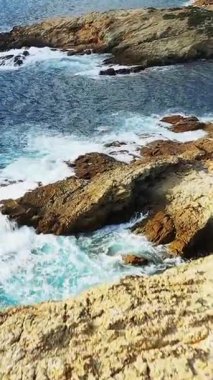 Delta du Fango, Korsika 'daki engebeli kayalık sahil şeridine çarpan dalgaların hava görüntüsü. Açık mavi deniz ve dramatik doğal manzara çarpıcı bir deniz manzarası yaratır..